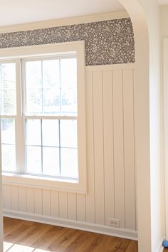 an empty room with wood flooring and white painted walls, along with a large window