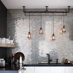 three lights are hanging over the kitchen sink