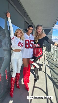 three women in white and red outfits posing for a photo on top of a building