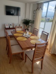 a dining room table with plates and bowls on it in front of a flat screen tv