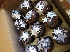 a box filled with chocolate cupcakes covered in white stars