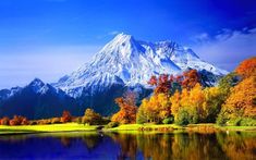 the mountain is reflected in the still water of the lake and trees are changing colors