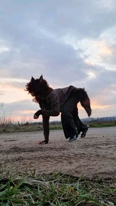 a person is playing with a dog in the dirt and grass at sunset or dawn