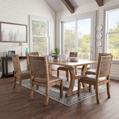 a dining room table and chairs in front of large windows