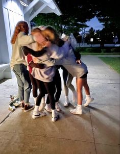 a group of young women standing next to each other on top of a cement slab