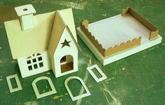 a paper model of a house with a star on the roof, and two smaller cardboard houses next to it