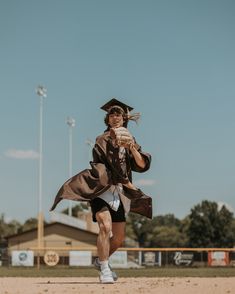 a man in a graduation cap and gown throwing a baseball