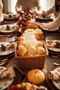 a table filled with bread and pumpkins for thanksgiving dinner guests to sit down at