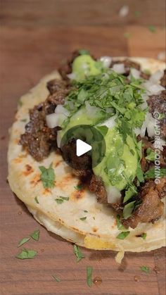 a tortilla topped with meat, onions and guacamole