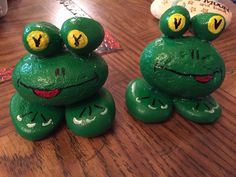 two green frogs sitting on top of a wooden table