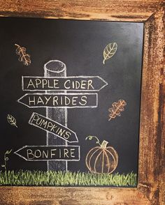 an apple cider sign in front of a chalkboard with the words apples cider, hayrises, pumpkins and bonfire written on it