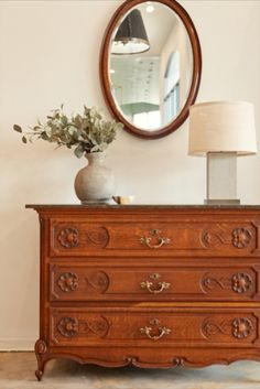 a wooden dresser sitting next to a mirror and lamp