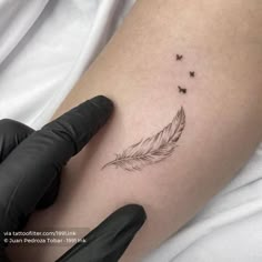 a woman's arm with a small feather and butterflies tattoo on the left thigh