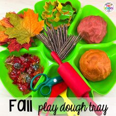 a green tray filled with different types of fall play doughs and tools on top of it