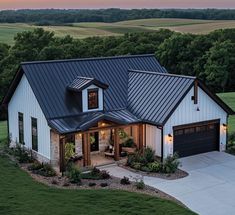 a large white house with a black roof and two garages on top of it