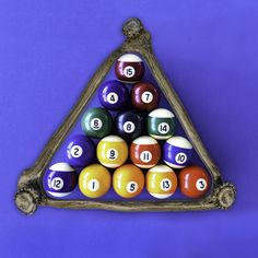 a triangle shaped rack with pool balls in it on a purple background and blue backdrop