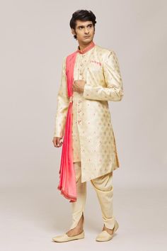 Gold sherwani with all over woven floral patterns and pink attached pleated side drape. Comes with dhoti pant.
Components: 2
Pattern: Woven
Type Of Work: Floral
Neckline: Mandarin Collar
Sleeve Type: Full
Fabric: Sherwani: Croma Heavy Jacquard, Dhoti Pant: Silk Dupion
Color: Gold
Other Details: 
Asymmetric hem
Embellished buttons
Closure:
Sherwani: Front button
Dhoti pant: Drawstring
Note: Pocket square worn by the model is not for sale
Occasion: Sangeet,Mehendi and Puja - Aza Fashions Traditional Drape Salwar Kameez For Ceremonies, Fitted Salwar Kameez With Naqshi In Traditional Drape, Navratri Kurta With Naqshi In Traditional Drape, Banarasi Silk Salwar Kameez With Traditional Drape For Reception, Reception Brocade Salwar Kameez With Traditional Drape, Brocade Salwar Kameez For Reception With Traditional Drape, Festive Reception Sherwani With Self Design, Festival Reception Sherwani With Self Design, Brocade Kurta With Traditional Drape For Reception