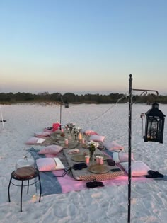 a picnic table set up on the beach with candles and plates in front of it