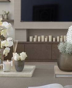 a living room with flowers and candles on the table in front of a flat screen tv