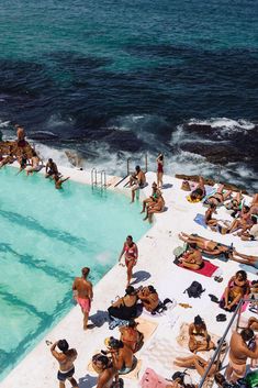 many people are sitting on the beach and swimming