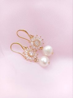 two pearl and crystal earrings on a pink background