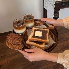 a person holding a plate with some food on it and two glasses of milk in front of them