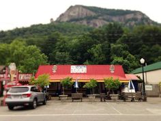 a red roofed restaurant with trees and mountains in the backgrouds behind it