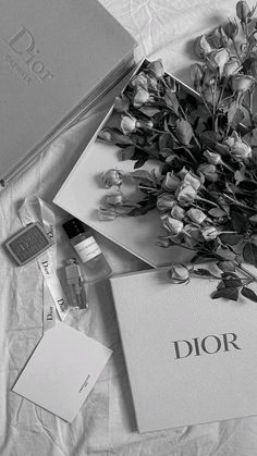 black and white photograph of flowers, notebooks, and other items on a bed