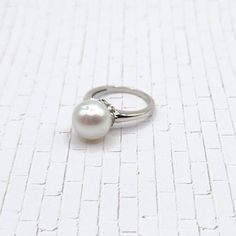 "Center Stone: Freshwater Pearl Center Stone Dimensions:  ~11mm Round - Setting: Platinum over Sterling Silver, Stamped \"925\" Size: 7 Condition: NEW - Brand New, Never Worn - This ring features a gorgeous, lustrous white/cream freshwater pearl.  The pearl sits high on the finger. It is a very classic and lovely setting. The setting is done in sterling silver with platinum overlay. Platinum is a very expensive finishing material that protects against tarnishing; it also enhances durability. Size 7. You'll be receiving the EXACT ring photographed, so please carefully examine the pictures to make sure that you'll love it! Your ring will be carefully packaged in a jewelry box. Your ring will ship in 1-3 days from Wisconsin." Classic Sterling Silver Pearl Ring With Round Cut, Classic Sterling Silver Pearl Drop Ring, Classic Silver Ring With Akoya Pearl, Classic Sterling Silver Pearl Ring, Classic Silver Round-cut Pearl Ring, Classic Silver Pearl Ring With Round Cut, Classic Round Pearl Ring With High Luster, Classic Round Rings With Pearl Drop, Classic Silver Round Cut Pearl Ring