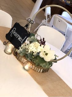 a basket with flowers on top of a table next to two candles and a sign that says reserved