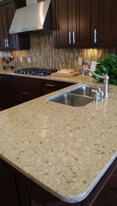 a kitchen counter top sitting next to a sink and oven in a room with wooden cabinets