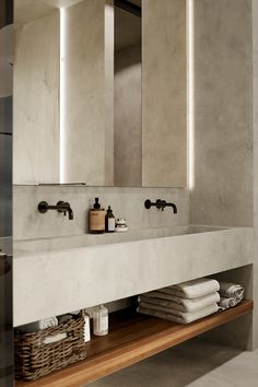 a bathroom sink with two mirrors above it and towels on the shelf next to it