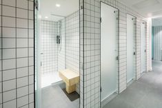 a white tiled bathroom with a bench in the corner