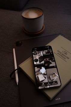 an iphone sitting on top of a book next to a cup of coffee