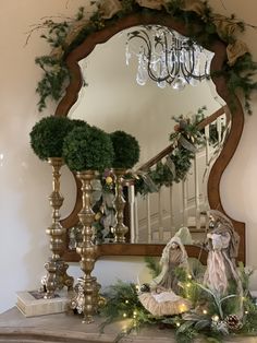 a mirror sitting on top of a mantle next to a christmas wreath and ornaments in front of it