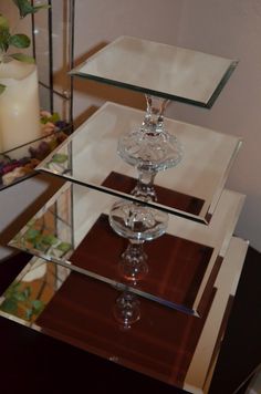 three glass vases sitting on top of each other in front of a mirror shelf