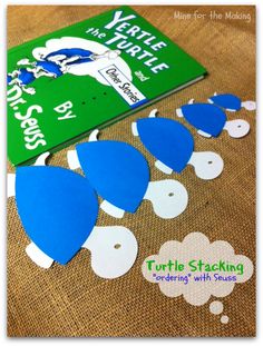 a book and some paper cutouts sitting on a brown cloth with the title turtle stacking