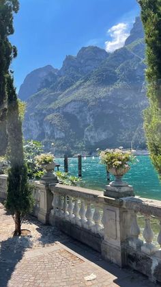 an outdoor area with stone walkways and flowers in vases on the wall next to water