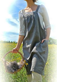 a woman holding a basket and walking through a field