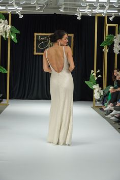 a woman is walking down the runway in a white dress with backless necklines