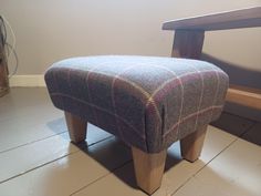 a foot stool sitting on the floor in front of a wooden bench with a plaid seat