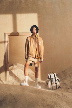 a man standing in front of a pile of sand next to a bag and suitcase