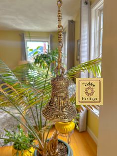 a bell hanging from a ceiling in a room with potted plants on the floor