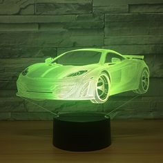 a green car shaped lamp sitting on top of a wooden table next to a brick wall