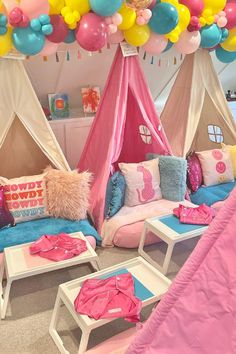 a room filled with lots of balloons and couches covered in pink, blue, and yellow