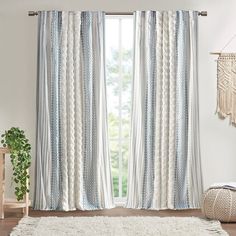 a white rug sitting next to a window with blue and white curtains on top of it