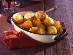 a bowl filled with potatoes sitting on top of a wooden table