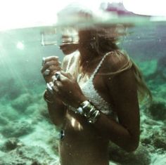 a woman standing under water holding a camera