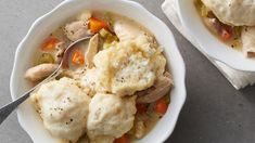 two white bowls filled with chicken and dumplings on top of a gray countertop