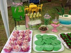 a table topped with lots of desserts and cakes covered in green frosted icing